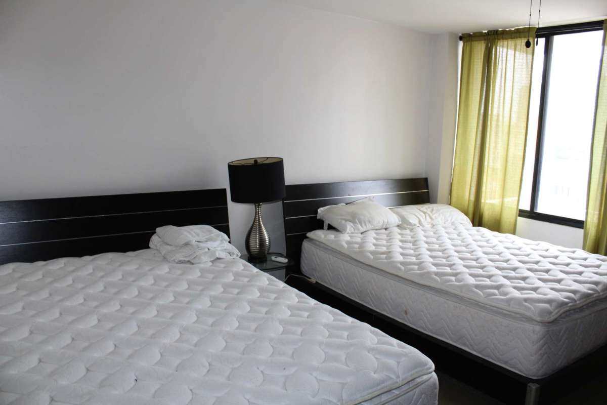 Bedroom with double beds, large windows, and minimal decor in Obarrio Plaza Panama apartment