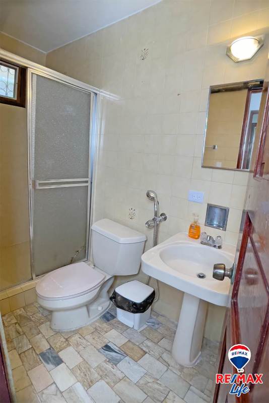 Traditional bathroom with marble countertop, double sink vanity, bathtub with frosted glass enclosure