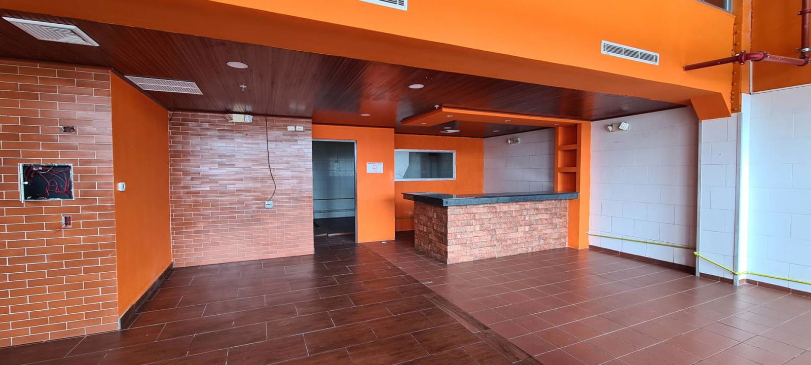 Interior with brick accent wall, orange walls, and bar counter Crystal Plaza retail unit Panama