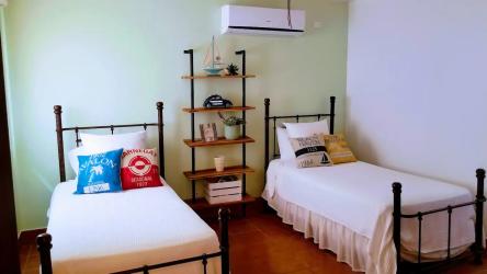 Comfortable twin beds bedroom with AC and green accent wall in luxury beach villa Buenaventura Panama