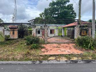 Exterior of deteriorated structure with metal fence and overgrown yard Paso Canoas Panama