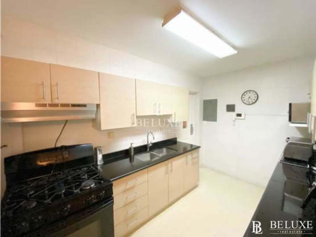 Residential street lined with trees, sidewalks, parked cars in gated Bethania neighborhood Panama