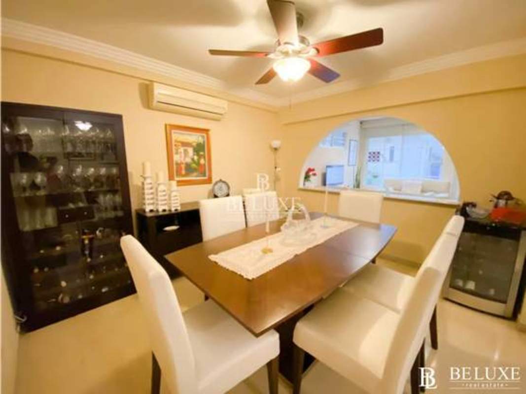 Dining room with wood table, white chairs, ceiling fan, beige walls in Bethania Panama house