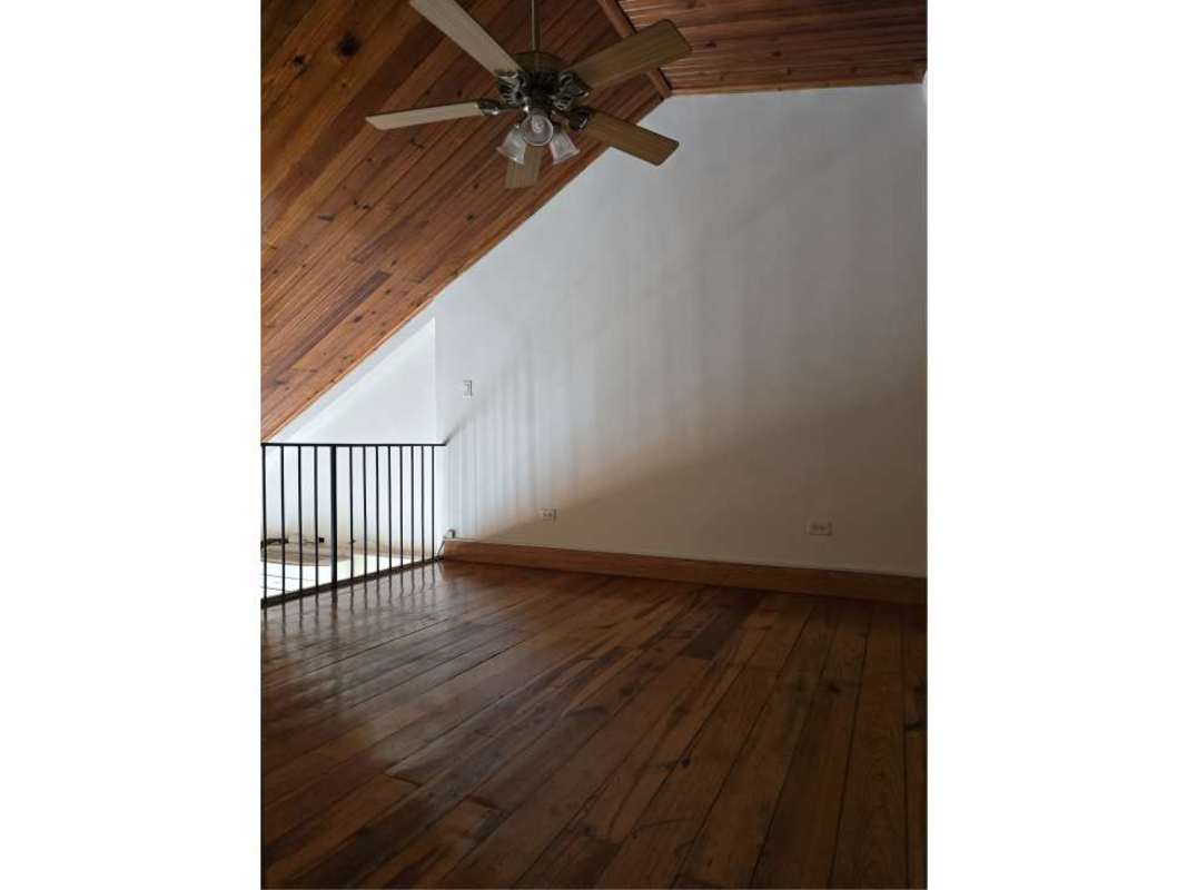 Interior loft area with sloped wooden ceiling, wood floors, ceiling fan in historic penthouse Casco Viejo Panama