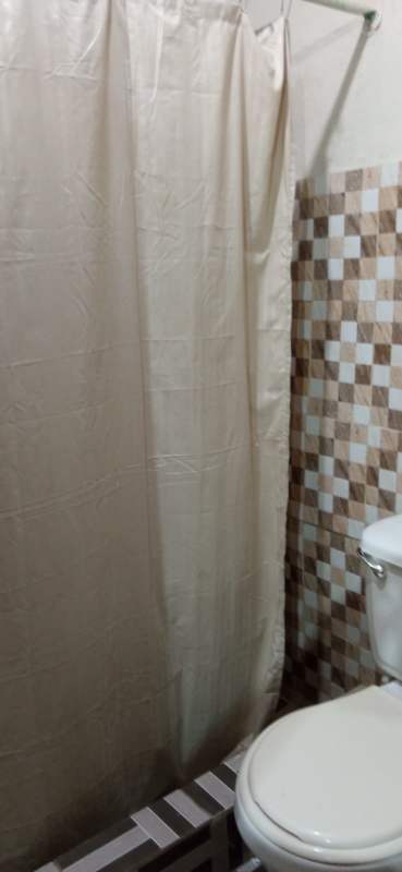 Simple bathroom with white tiles, shower and toilet in studio rental Panama