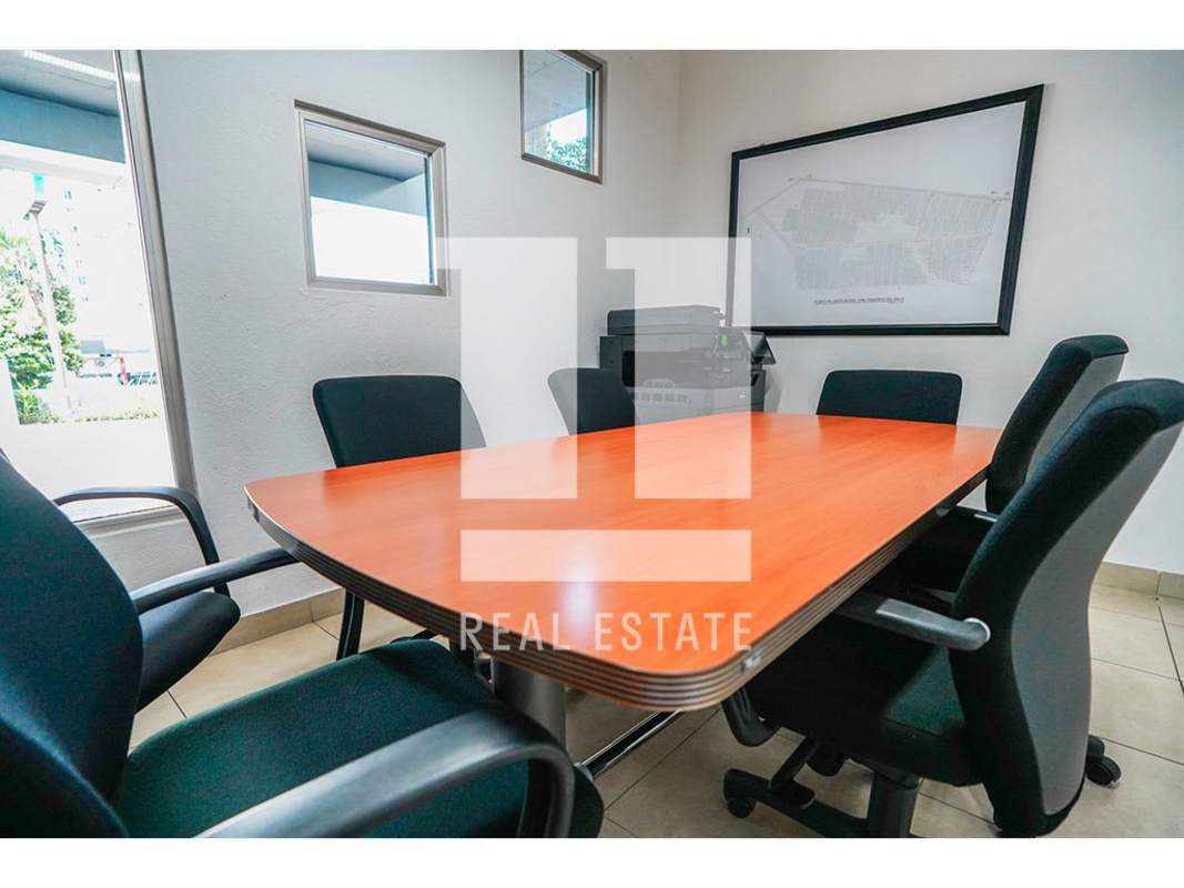 Meeting room with wooden table, black chairs, and windows in Calle 50 commercial building