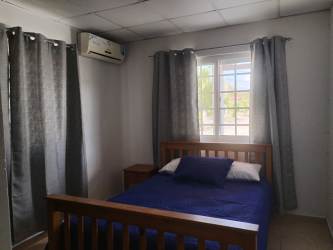 Two single beds with blue covers and window with curtains in Las Villas de Penonomé Penonomé Panama
