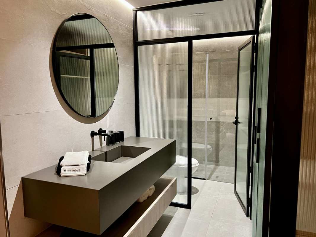 Modern bathroom with double vanity sinks, frosted glass shower, minimalist decor at PH Uruguay Bella Vista Panama
