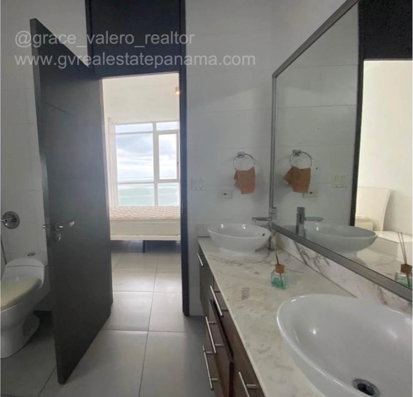 Spacious contemporary bathroom with large mirror, vessel sinks on marble counter, glass shower PH Element Panama