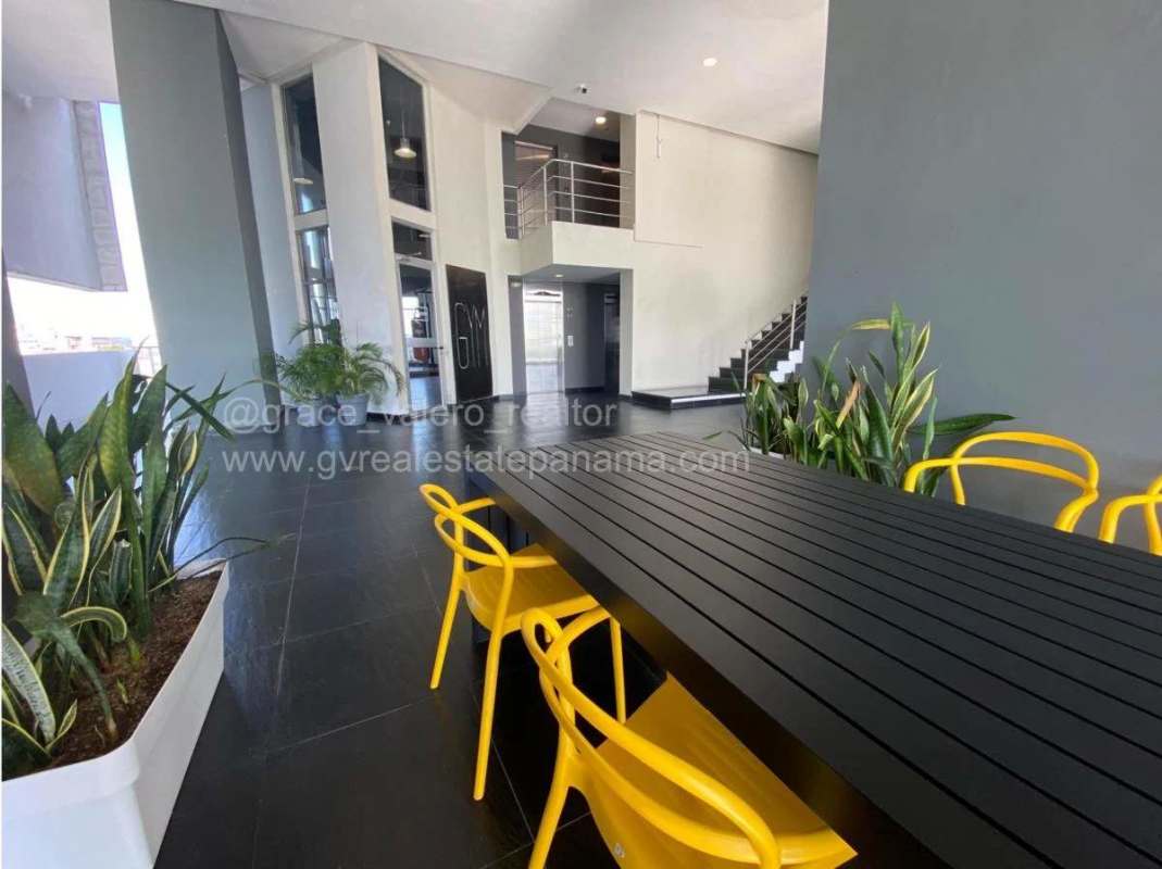 Double-height lobby with yellow chairs, black table, large windows PH Element Panama City