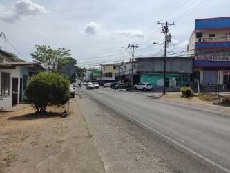 Urban street with commercial buildings, cars parked along road and retail activity La Chorrera Panama