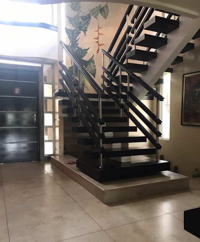 Curved staircase with metal railing, large windows and pendant lights in a modern Altos de Panamá house