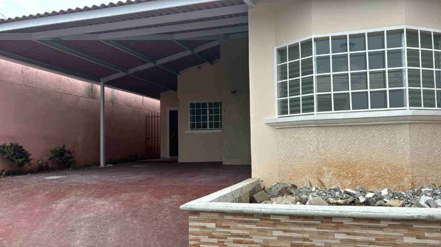 Backyard view with grass lawn, covered patio, and enclosed fence in Las Quintas San Antonio Panama
