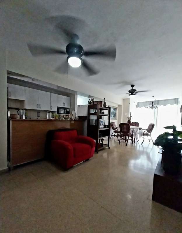 Interior open plan kitchen dining area red chair ceiling fans in apartment Panama
