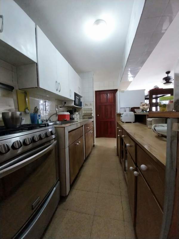 Kitchen with wooden cabinets, microwave, stove and tiled backsplash in Panama apartment