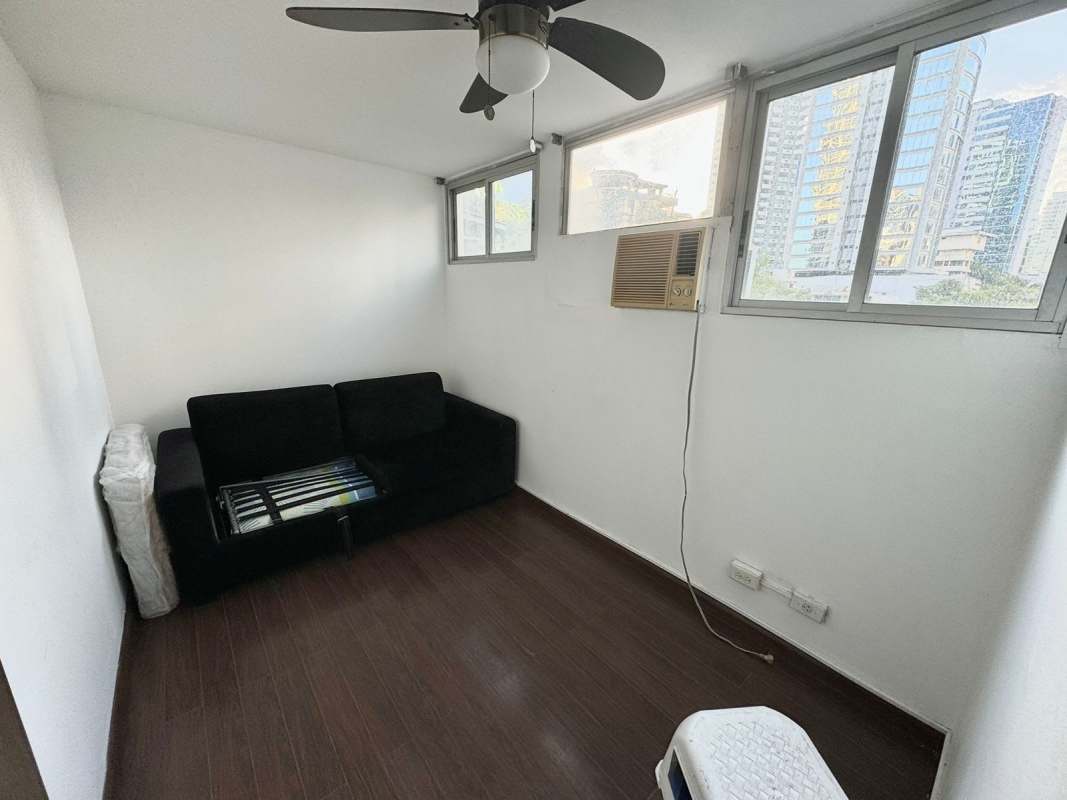 Compact living or den with wood flooring, window AC and city view PH Arcelia El Cangrejo