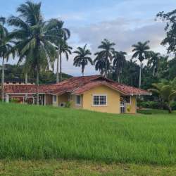 Single story house with red tiled roof on grassy lot in Howard neighborhood Panama Pacifico