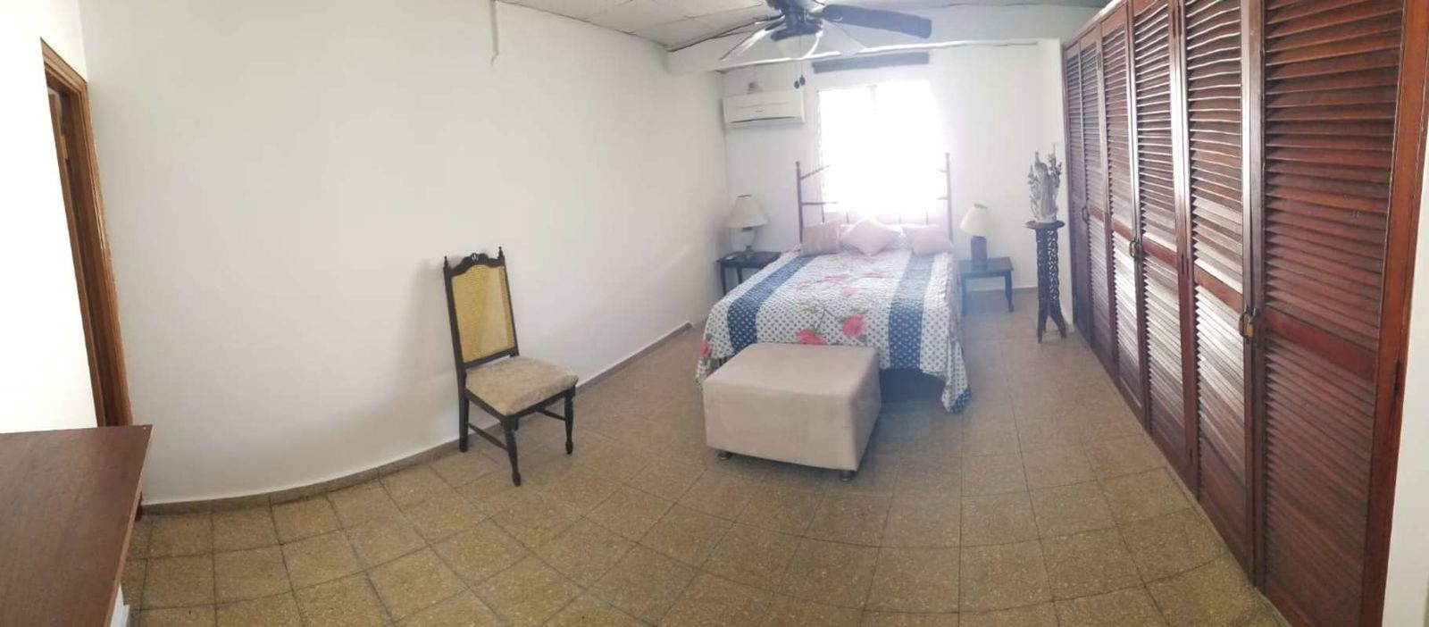 Spacious master bedroom with traditional furniture, closet, AC unit and ceiling fan in house in Chanis Panama City