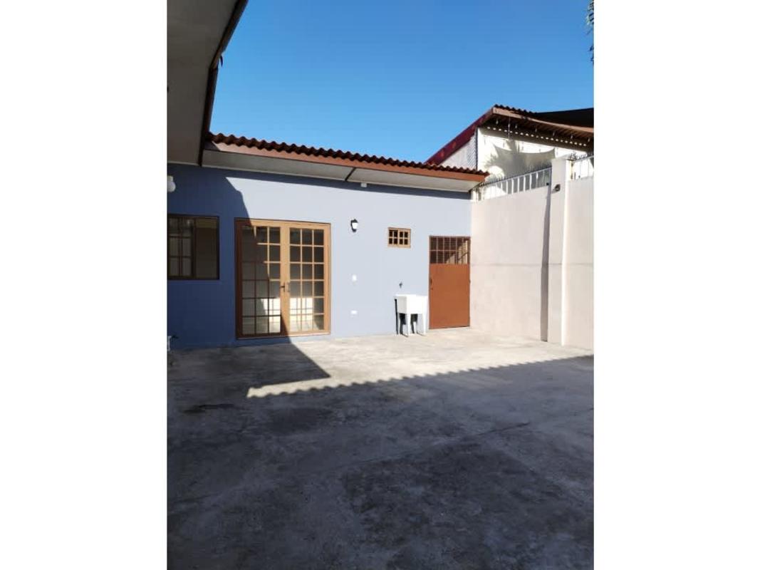 Backyard with secure fence, open concrete patio, blue exterior wall at Brisas del Golf house Panama