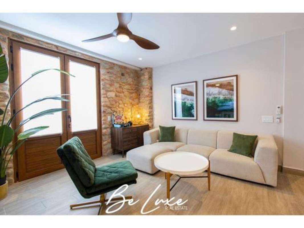 Rustic-modern living room with stone accent wall, sofa, wood doors PH La Cuadra Casco Viejo