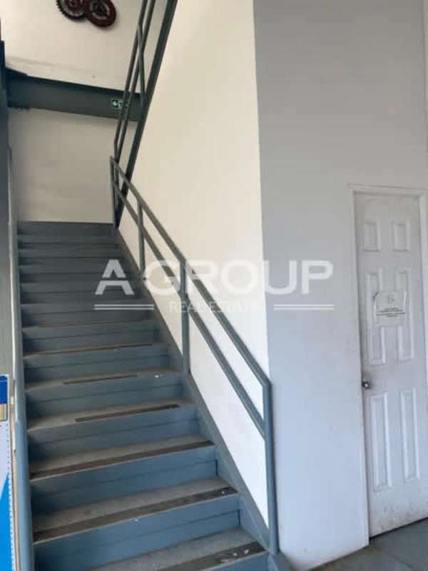 Industrial metal staircase leads up to office mezzanine inside warehouse Panama Zona Uno