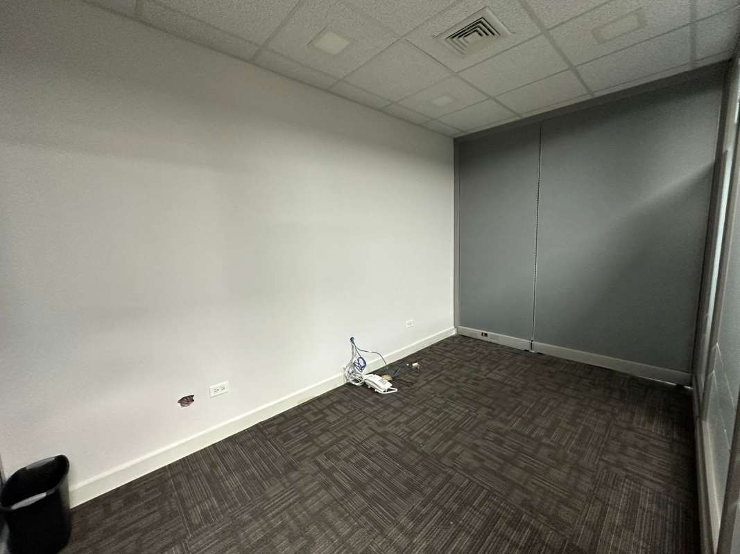 Small office with frosted glass walls, white desk and chairs and orange accent chair in Torre Oceanía Panama