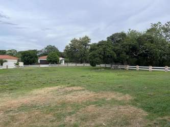 Large flat residential land plot with green grass and trees at Hacienda Pacífica San Carlos
