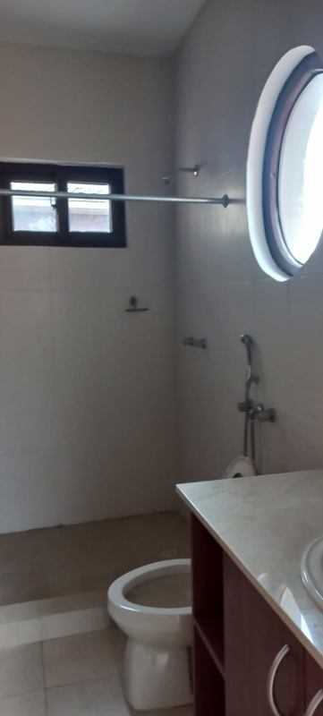 Modern minimalist bathroom with shower, round window, and white tiles in El Doral Costa Sur Panama