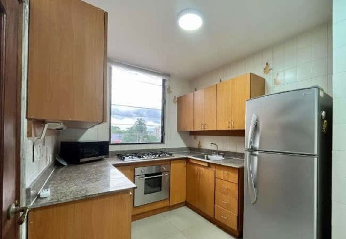 Kitchen with granite counters, wood cabinets, and appliances at PH Metropolis Panama City