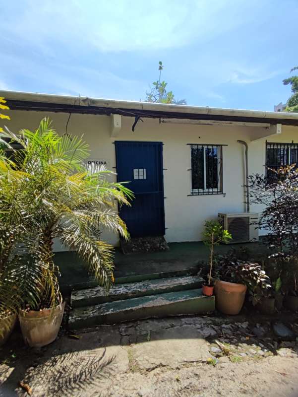 Exterior office building with blue door, barred windows, potted plants commercial complex for sale in Panama City