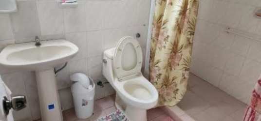 Traditional bathroom with pedestal sink, toilet, floral shower curtain in rural Panama farmhouse.
