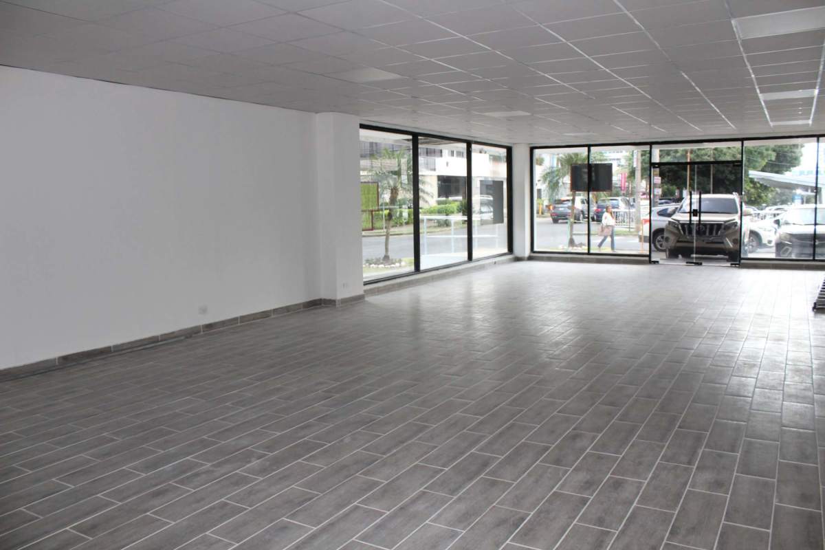 Spacious empty commercial unit with large glass windows and gray tiled flooring in Panama City