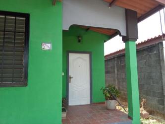 Covered entry porch with white door in green house rental Brisas del Golf Arraiján Panama