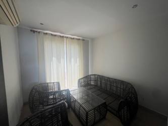 Living room with large window, wicker furniture, and tile floor in Ibiza Beach Residence Panama