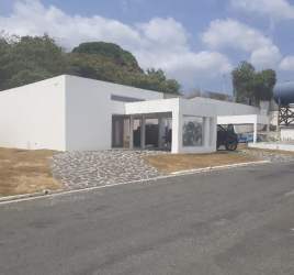 White facade beach villa with flat roof, large windows, landscaping at Ibiza Beach Residence Panama