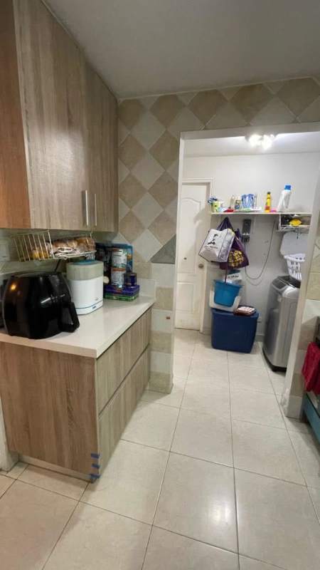 Kitchen with wooden cabinets and adjoining laundry room in The Springs Condado del Rey duplex house Panama