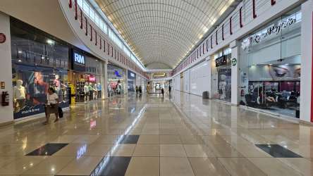 Spacious interior corridors of Westland Mall with numerous retail stores, high ceilings, glass storefronts.