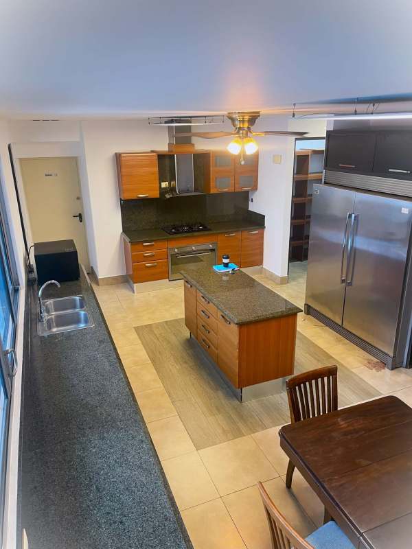 Modern kitchen with granite island stainless appliances and wood cabinetry PH Ten Tower Panama City