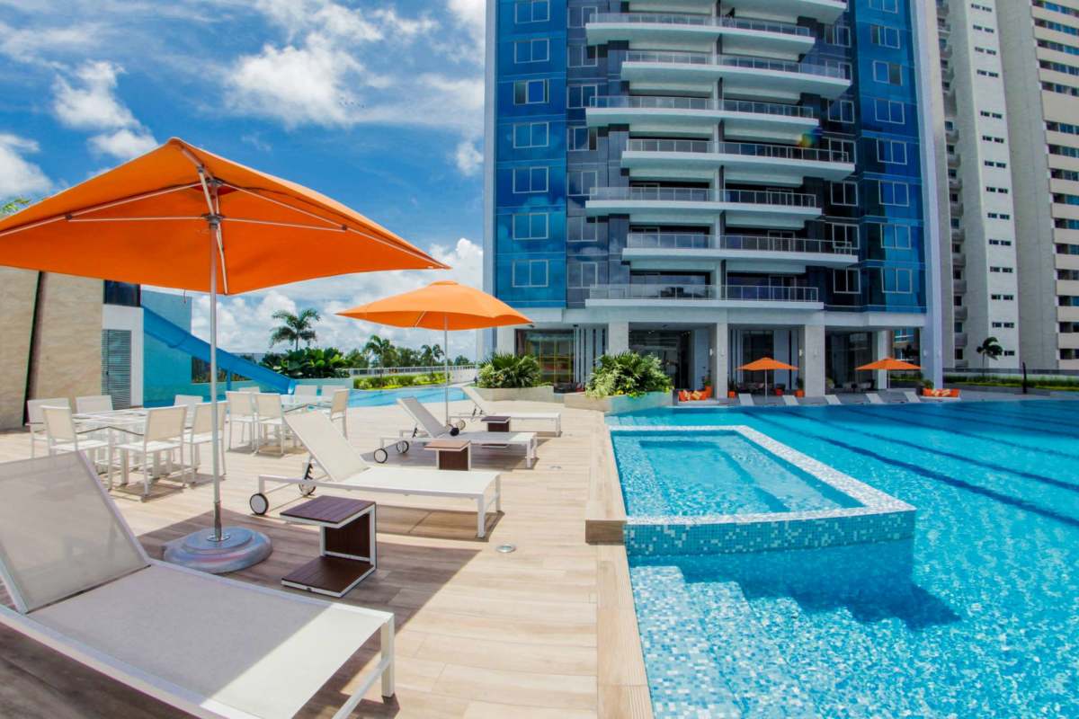 Luxury infinity pool with lounge chairs, umbrellas, and palm trees at PH Regalia Costa del Este Panama