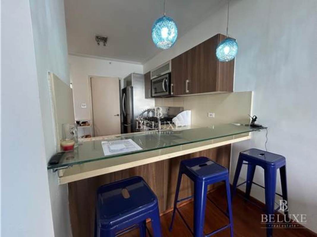 Open kitchen with wood cabinets and breakfast bar in Punta Pacifica apartment