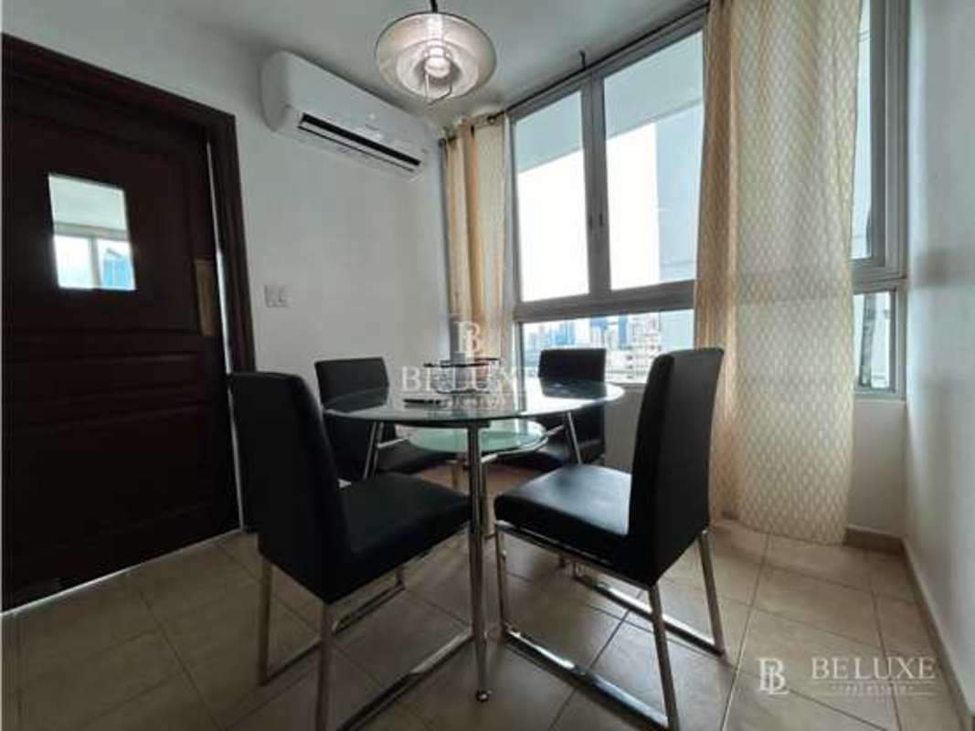 Dining space with glass table, black chairs and city view at PH Sol Marina