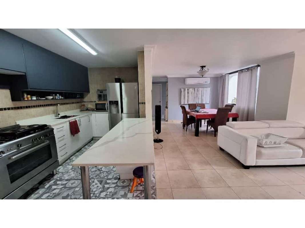 Contemporary open kitchen with marble island, dining area with red cover, modern appliances