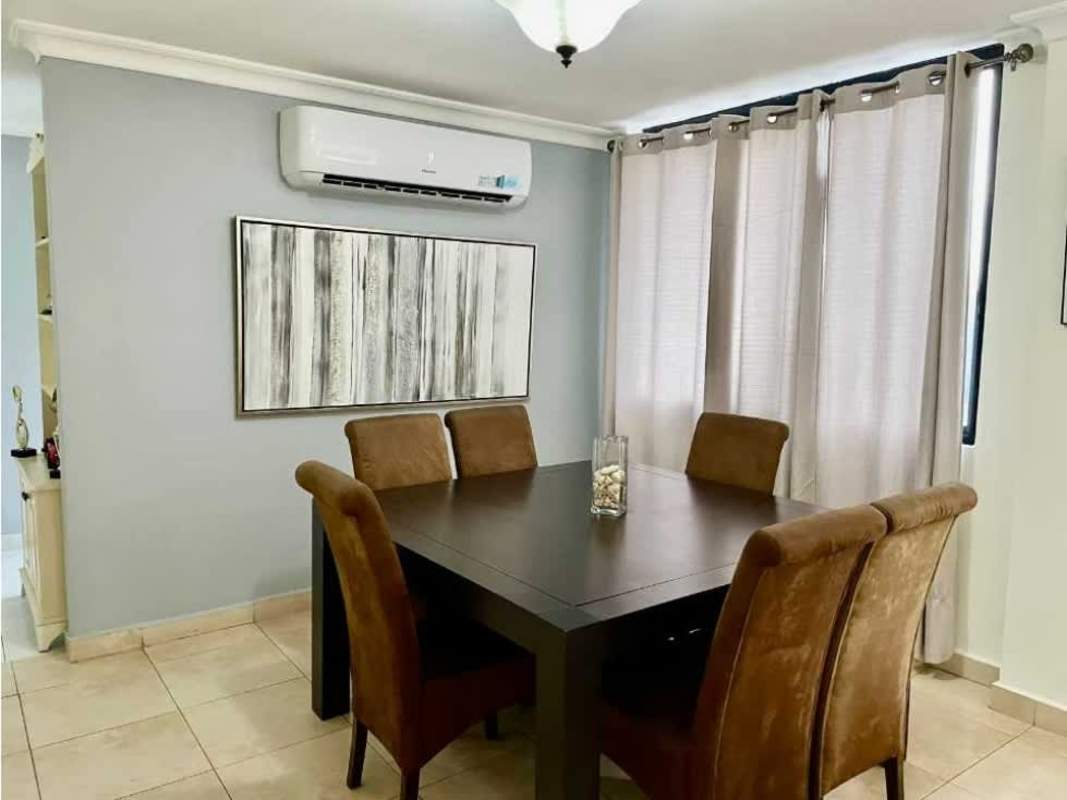 Dining space with large dark wood table, upholstered chairs, AC and wall art Panama