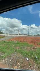 Sight through vehicle window of fenced flat land ready for development under blue sky in Arraiján Panama