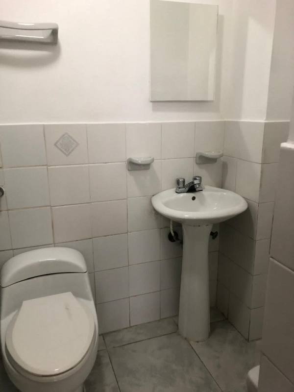 Minimalist bathroom with white tiles, pedestal sink and mirror in PH Gamma Real Panama