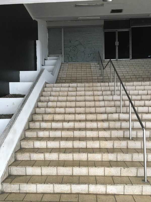 Street-facing entrance to commercial rental with metal handrails and glass doors in Panama City.