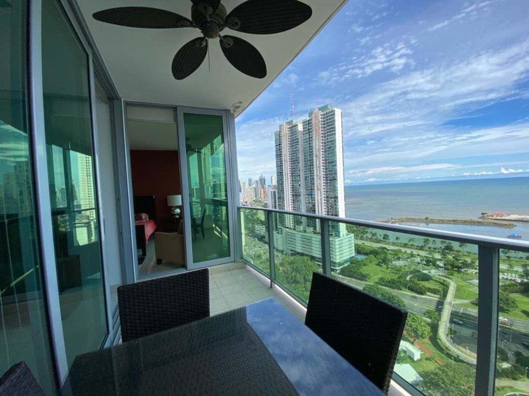 Modern living room with sectional sofa, large glass doors opening to ocean balcony, PH BICSA Panama City
