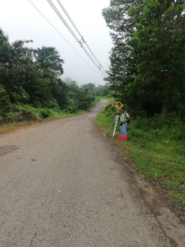 Rural asphalt road with survey equipment and power lines near Llano Cartí farmland Chepo Panama