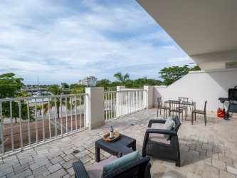 Bright furnished living and dining room with glass doors opening to terrace and marina view