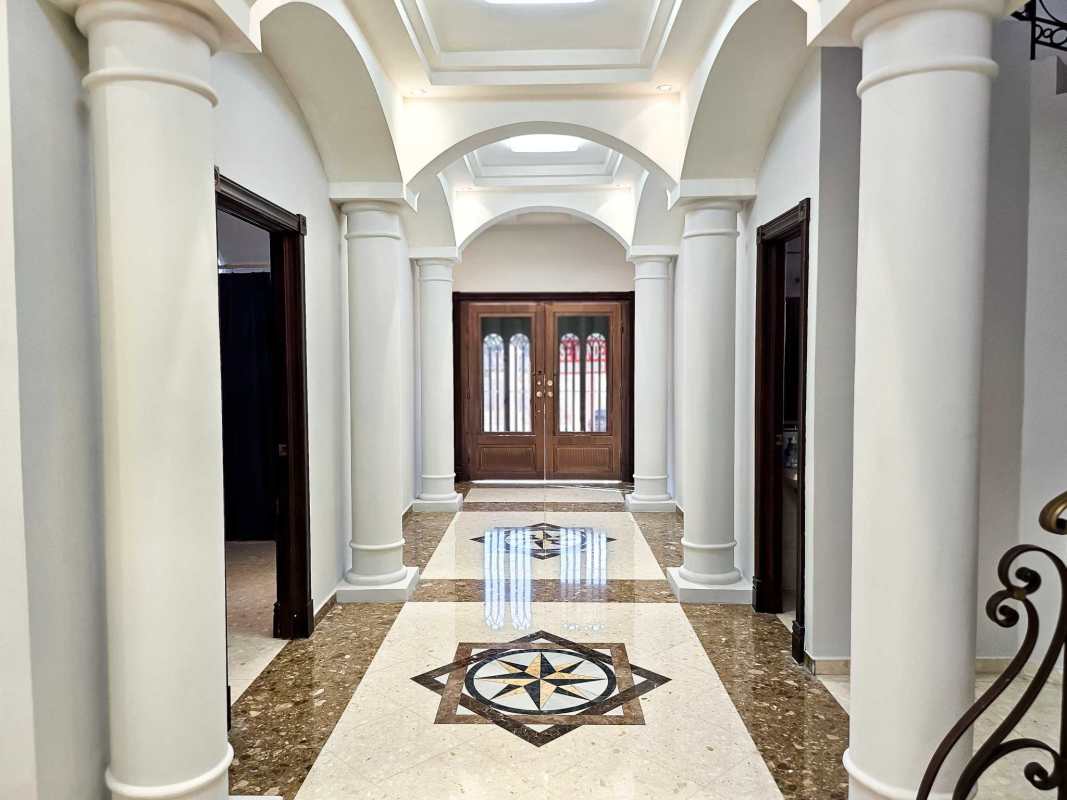 Grand neoclassical hallway with arched ceilings and marble flooring in luxury home for sale Panama City
